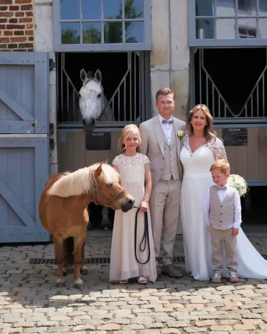 Sanne en Nicky met twee kinderen en een pony voor een stal met blauwe deuren